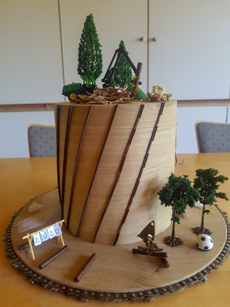 Doktorhut aus Eiche für Joachim B. Heppelmann mit entrindendem Harvester, Fichtenpolter und -rinde, Bauteilen der Entrindungswalzen (braune Streifen) usw. Foto: C. Bennemann, HSWT