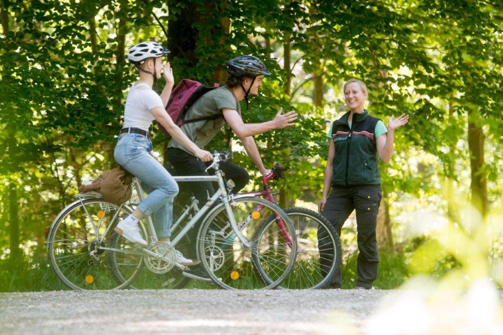Radfahrer begegnen einer Försterin im Wald. Foto: T. Hase, StMELF Radfahrer begegnen einer Försterin im Wald. Foto: T. Hase, StMELF